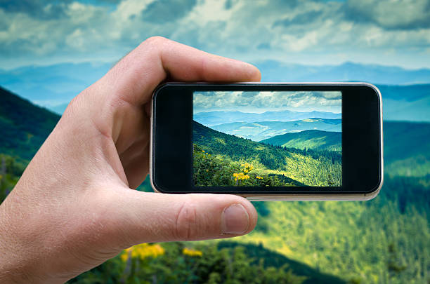 istock phone in a man's hand, mountain landscape photographs on 609820638