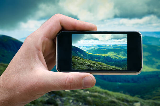 istock phone in a man's hand, mountain landscape photographs on 609820728