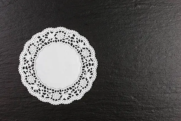 white paper doily on black slate background