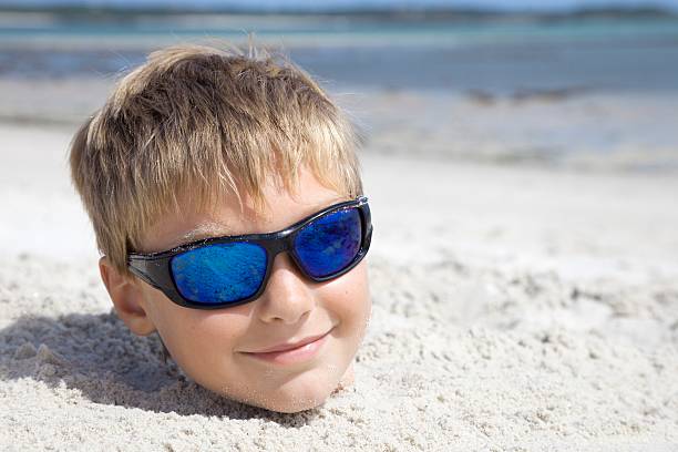 istock Boy on holiday buried in the sand 609823332