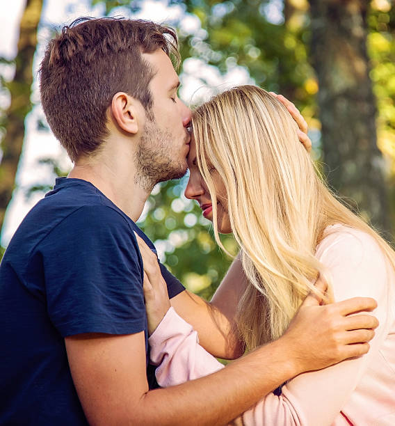 istock Young man kissing his woman's forehead in the park. 609823370