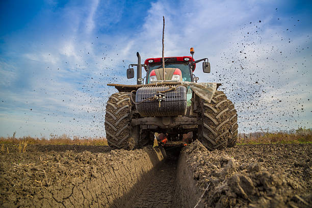 Tractor with double wheeled ditcher digging drainage canal.