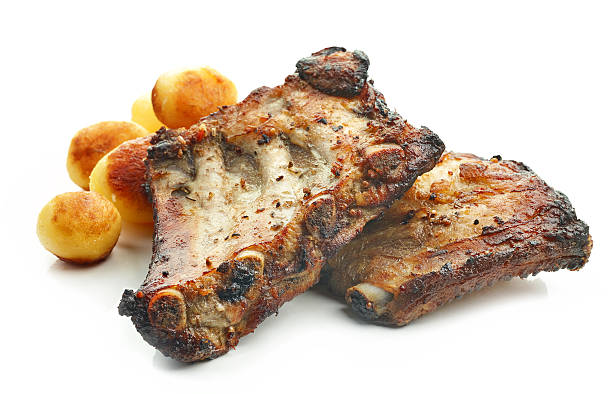 on the table is a plate of grilled ribs, stewed cabbage, baked potatoes and salad letuk