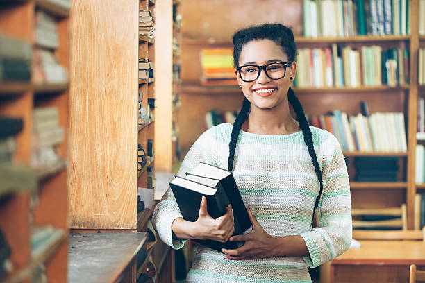 istock Smiling female student holding books at library 609834692
