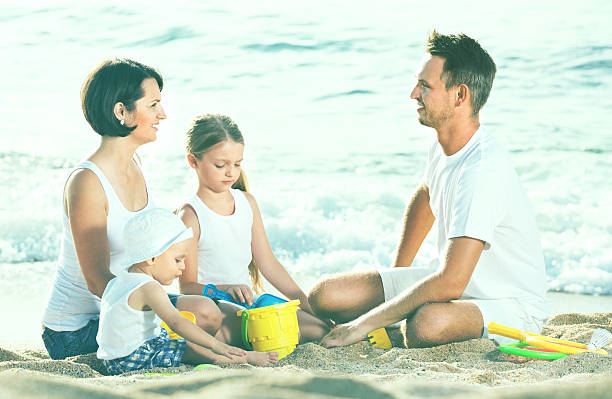 istock Parents with two kids playing with toys on beach 609838444