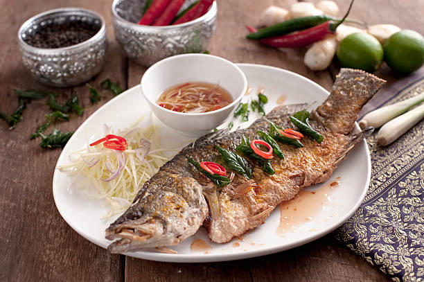 istock Fried barramundi fish with fish sauce on white plate with 609904886