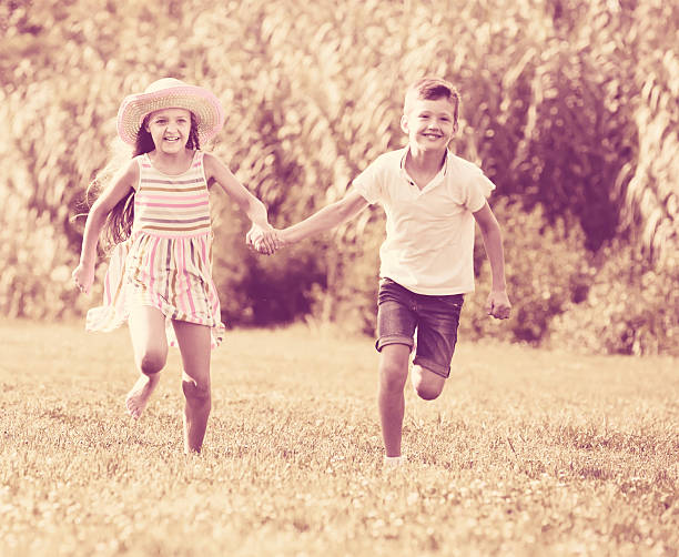 istock two cheerful children active playing and running outdoors 609905196