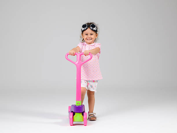 istock Cute little girl riding scooter in studio 609905302