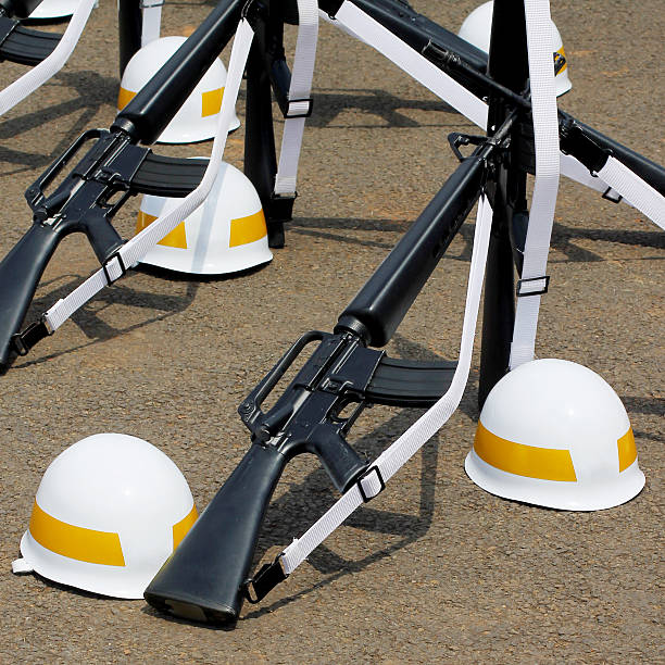 Formation of assault rifles and yellow striped helmets laid on the ground.