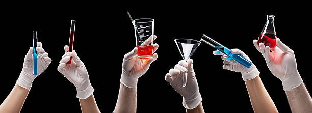 Mains tenant la verrerie de laboratoire avec des liquides - Photo