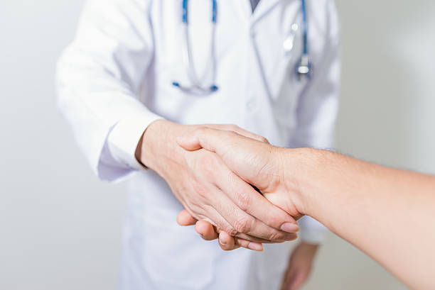 istock doctor shaking a patient's hands on white background 609910016