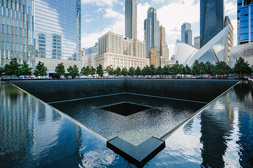 New York, USA - September 7, 2016:  South pool memorial commemorating the victims of the 11 september terror attack in 2001. New York architecture in the background.