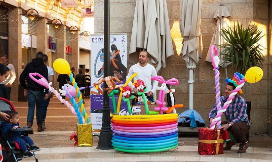 Jerusalem, Israel - February 19, 2014: Balloon twisters specializing in entertaining events promoting themselves at Mamilla pedestrian promenade and unidentified children looking.