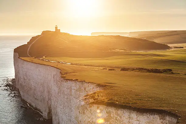 Panoramic view of Seven Sisters cliffs with lighthouse and sea on background at sunset. Photo taken from Beachy Head, on Eastbourne side, with backlight sunset. Travel and nature concepts.