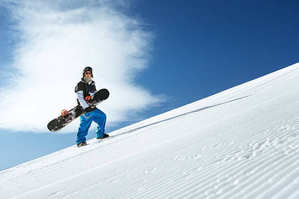 Snowboarder is on the rise  the blue sky backdrop Snowboarder goes hill on the blue sky backdrop in mountains. Sheregesh, Siberia, Russia Sheregesh stock pictures, royalty-free photos & images