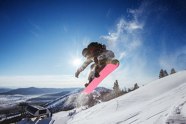 Snowboarder jumps on blue sky backdrop in mountains trick Bright color snowboarder jumps on blue sky backdrop. Sheregesh, Siberia, Russia Sheregesh stock pictures, royalty-free photos & images