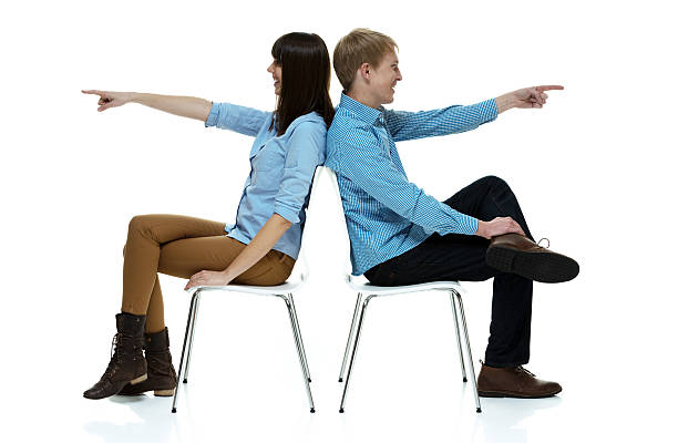 istock Smiling couple sitting and pointing away 609919192