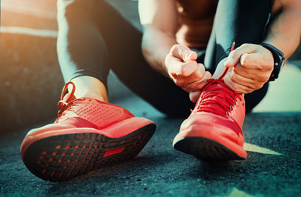 Tying sports shoes Man tying jogging shoes.He is running outdoors on a sunny day. marathon stock pictures, royalty-free photos & images