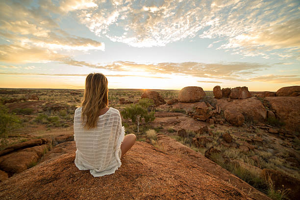 Caucasian female meditating at sunrise Young woman at the devil's Marbles sitting on a boulder exercises yoga at sunrise. Devils Marbles Conservation Reserve, Northern Territory, Australia. northern territory australia stock pictures, royalty-free photos & images