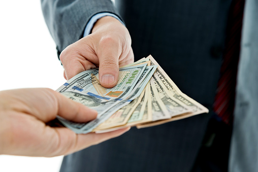 Closeup of businessman hands giving money.