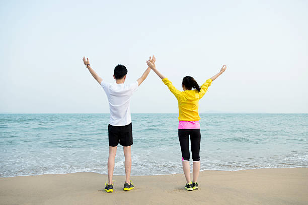 istock Young couple with their hands raised on beach 609931700