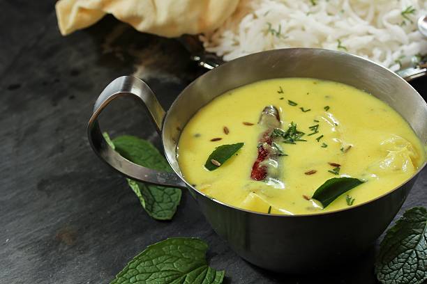 Gujarati Kadhi served with rice and papad, selective focus Gujarati Kadhi served with rice and Papad - Indian vegetarian curry made of buttermilk and Chick pea flour karahi stock pictures, royalty-free photos & images