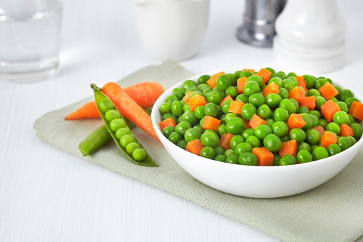 Fresh bowl of green beans and cubed carrots on white background