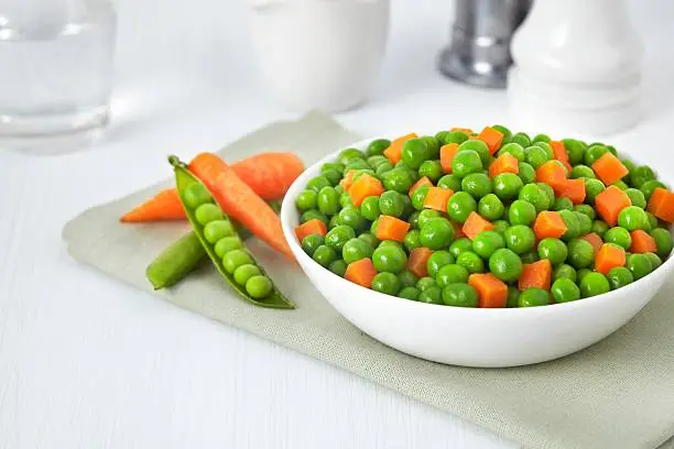 Photo of Fresh bowl of green beans and cubed carrots on white