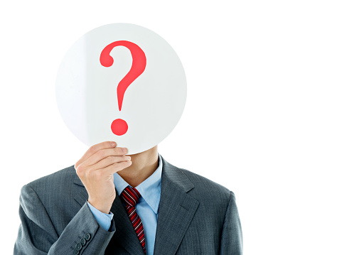 Confused businessman holding question mark against white background.