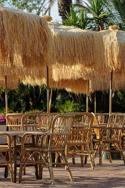 istock Tables and wicker chairs with straw sunshades in the restaurant 609936582