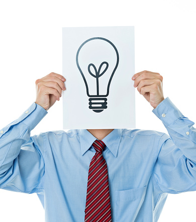 Businessman holding a paper with light bulb symbol against white background.