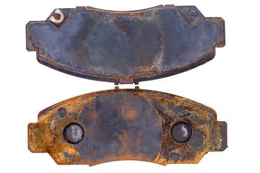 Pair of old rusty worn brake pads or callipers viewed from above on a white background in a concept of maintenance and repair