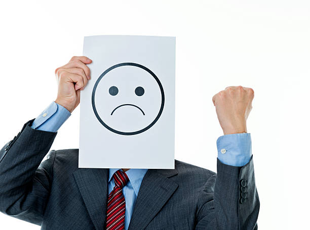 Businessman holding paper with sad face against white background.