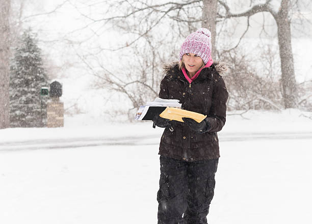 istock Woman gets mail during snowstorm 609941760