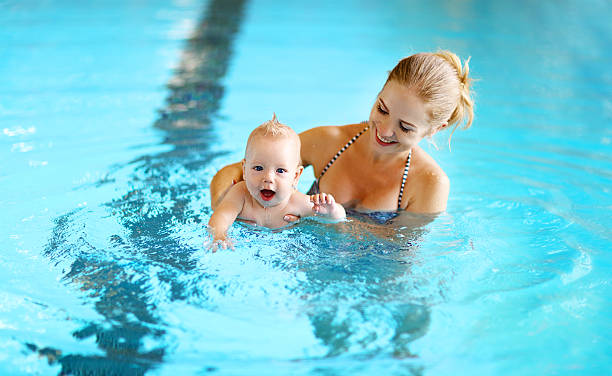 istock mother teaching baby swimming pool 609942702