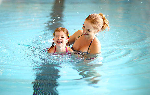 istock mother teaching child daughter swimming pool 609942746