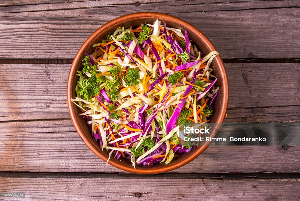 Fresh salad of autumn vegetables Fresh salad of autumn vegetables - purple and green cabbage, carrots, green onions, parsley - in a clay bowl on rustic wooden table, copy space. Rich and vitamin vegetarian lunch Autumn Stock Photo