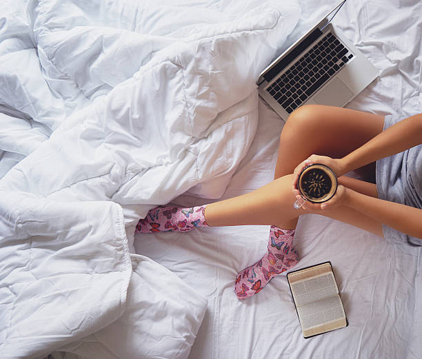 Fille lisant un livre et buvant du café sur le lit - Photo