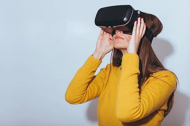Photo of Young woman using virtual reality glasses