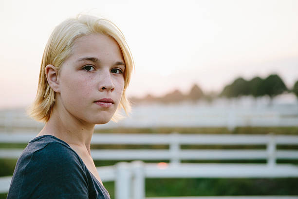 retrato: linda adolescente rubia mira en serio a la cámara - foto de stock