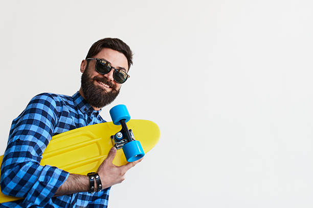 istock bearded hipster in checkered shirt holding yellow skateboard 609952944