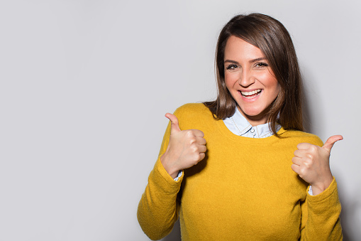 Portrait of a young smiling woman holding a thumbs up