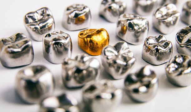coronas dentales de oro y metal. aislado. - corona-dental fotografías e imágenes de stock