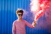 young black hipster man smiling and holding a colorful pink