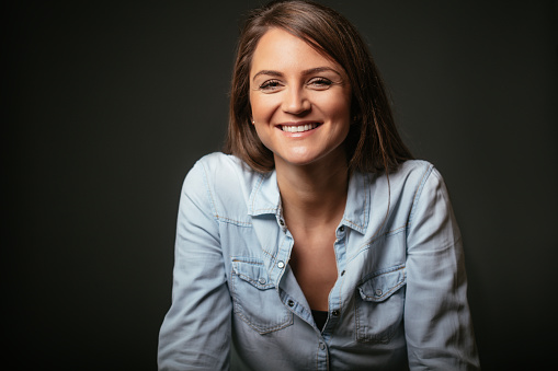 Portrait of a young smiling woman; studio shot isolated on black