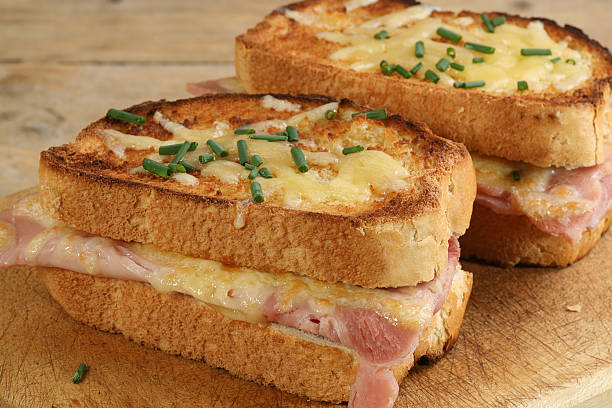 croque monsieur two slices of croque monsieur cheese and ham on a wooden board toasted sandwich stock pictures, royalty-free photos & images