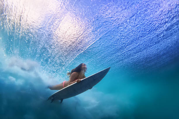 hermosa chica surfista buceando bajo el agua con tabla de surf - surfing surf wave extreme sports fotografías e imágenes de stock