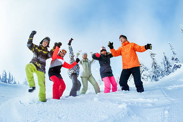 istock Happy snowboarders posing on blue sky backdrop in mountains 610012152