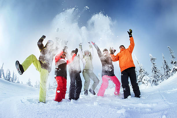 istock Happy snowboarders posing on blue sky backdrop in mountains 610012304