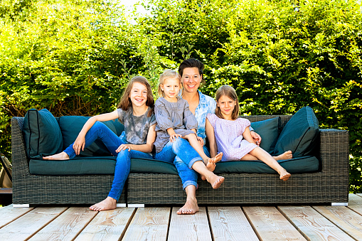 mother with her three daughters sitting on a couch in the garden.